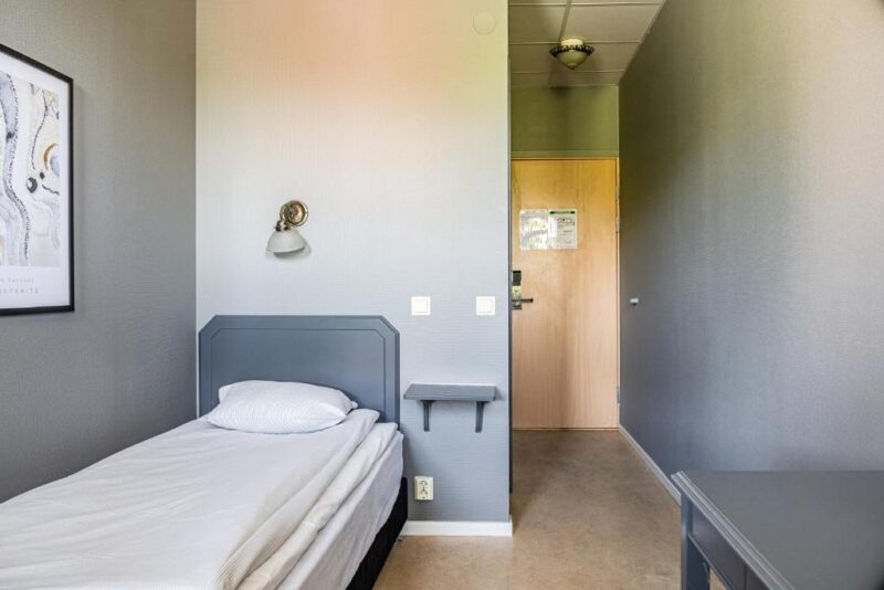 Enkelrum på Hotel Expo i Stockholm med smal planlösning, grå väggar och enkel säng – praktiskt boende för ensamresenärer som vill ha ett lugnt, prisvärt rum med stilren känsla.